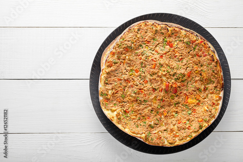 Lahmacun traditional turkish pizza with minced beef or lamb meat, paprika, tomatoes, cumin spice, parsley baked spicy middle eastern arabian food on white wooden table background