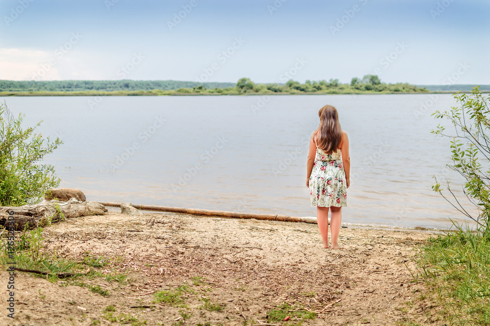 Girl brunette stands on the river bank in sundress Girl brunette stands on the river bank in sundress