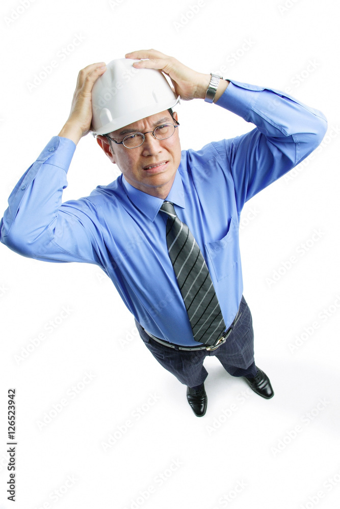 Man wearing hardhat frowning, hands on head Man wearing hardhat frowning, hands on head
