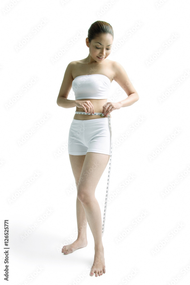Young woman measuring her waist with tape measure Young woman measuring her waist with tape measure
