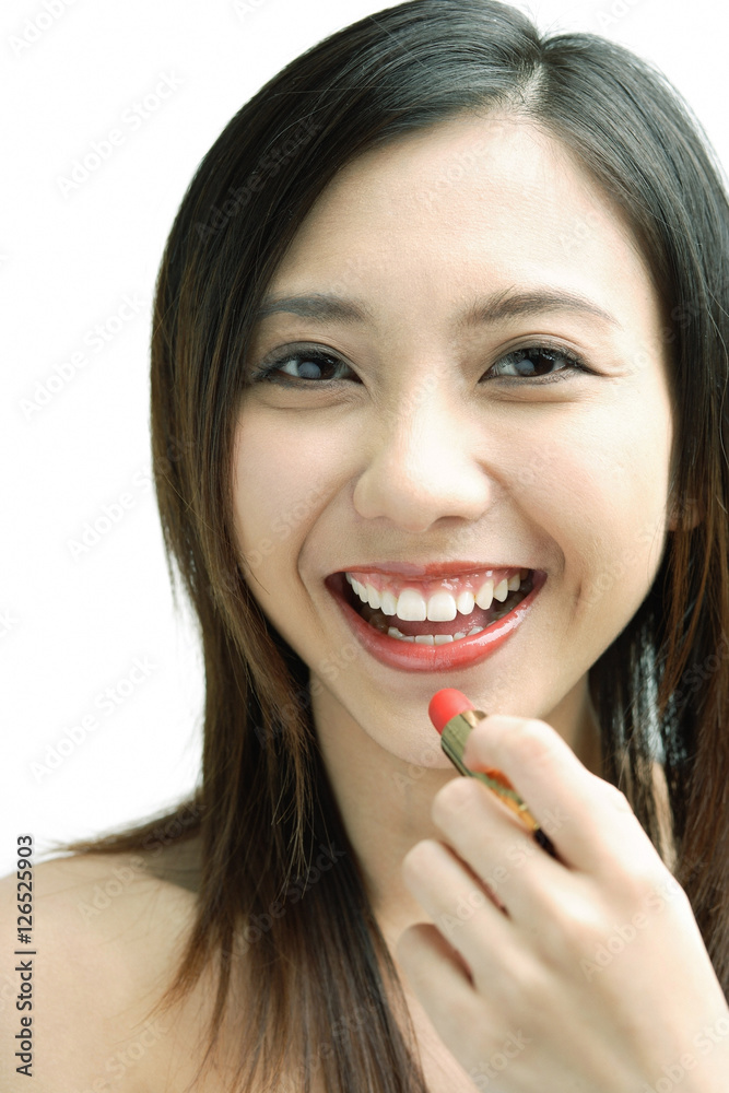 Woman smiling at camera, putting on lipstick Woman smiling at camera, putting on lipstick
