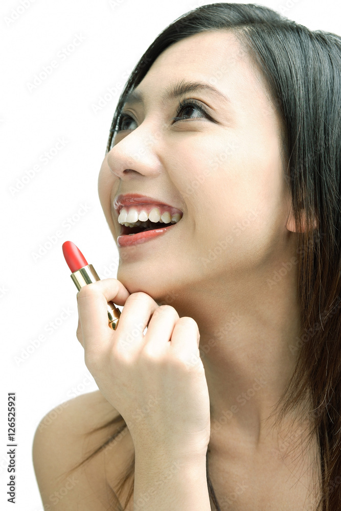 Woman smiling looking away, holding lipstick Woman smiling looking away, holding lipstick