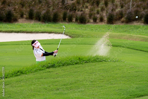 The women golfers hit golf balls off the sand motion blur