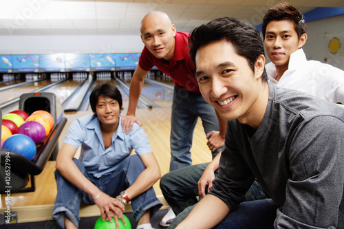 Four men in bowling alley, looking at camera