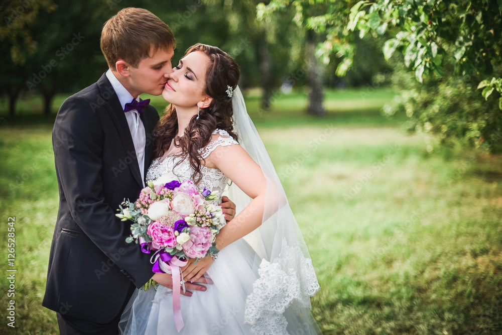the bride and groom kissing in nature, a beautiful bouquet Sunny day the bride and groom kissing in nature, a beautiful bouquet Sunny day