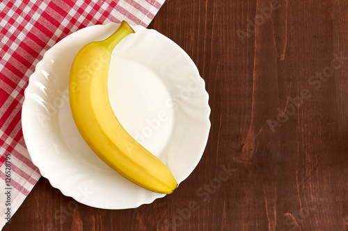 One banana on white plate. Concept image for diet. Top view with plenty of copy space