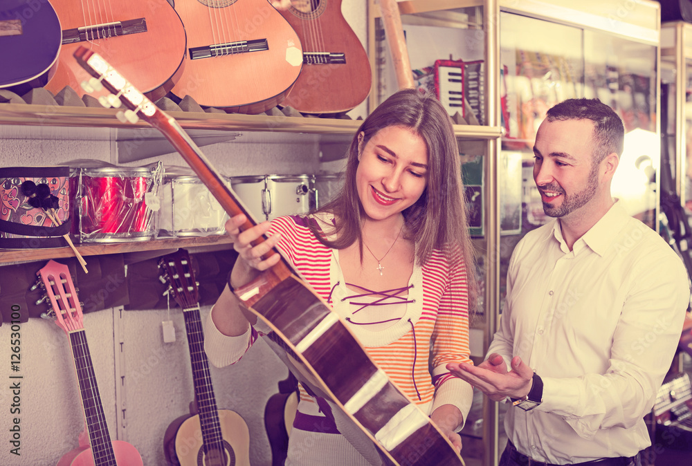 Happy couple selecting acoustic guitar in shop