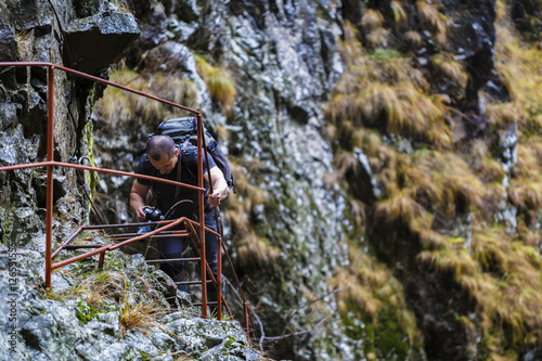 Caucasian hiker climbing on a safety chains through a very diffi