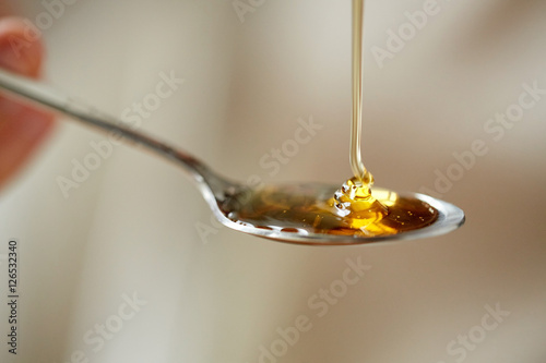 close up of honey pouring to teaspoon photo