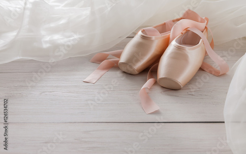 Pink ballet pointe shoes and tutu on white wood background