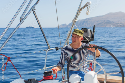 Man drives sailing yacht at the sea. Luxery boats.