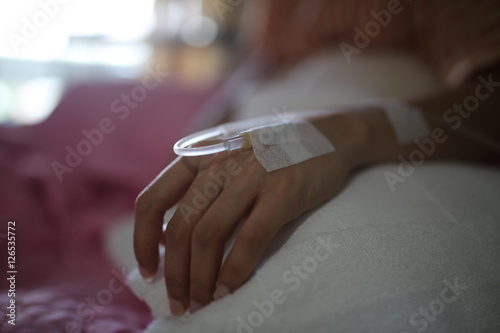 patient hand inject with saline on the hospital bed