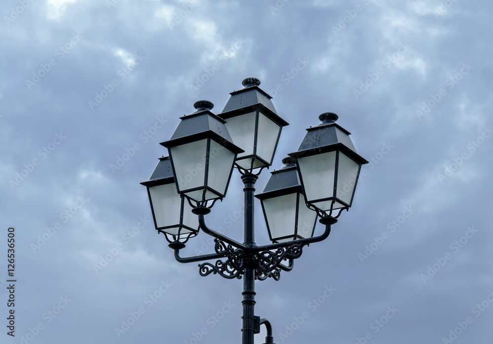Old big street lamppost with cloudy sky