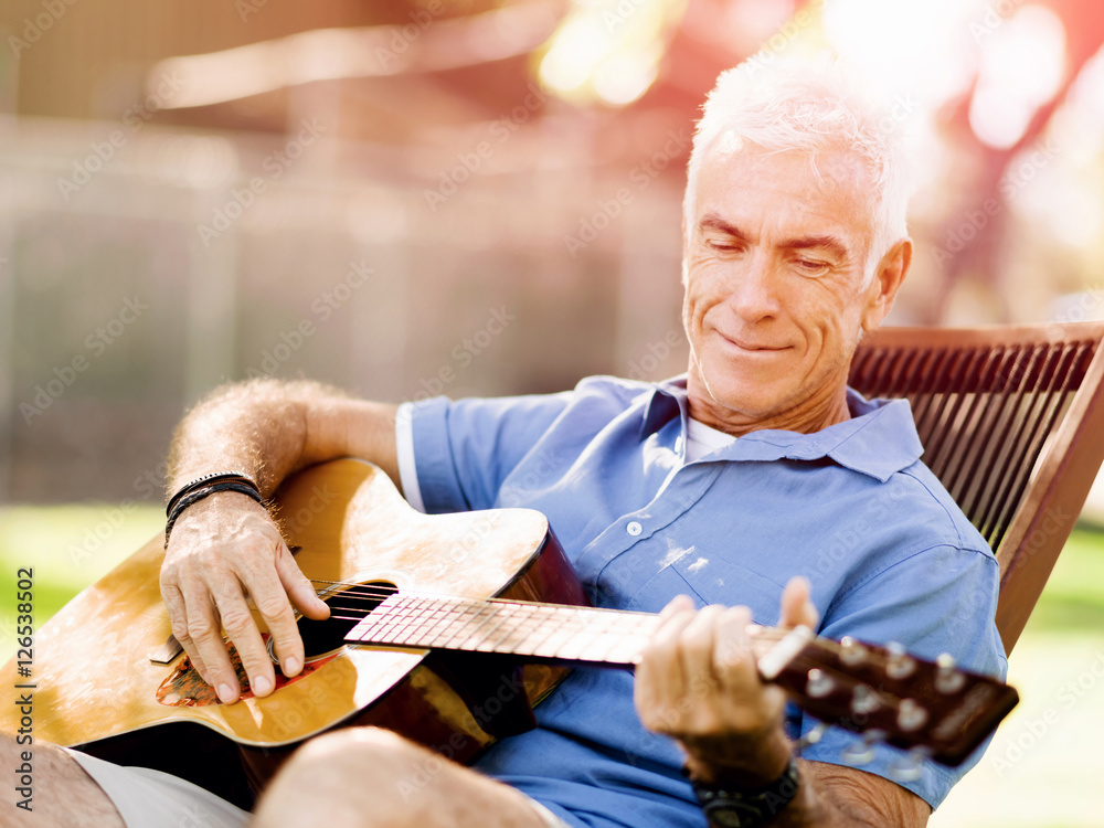 Senior man plying guitar outdoors Senior man plying guitar outdoors