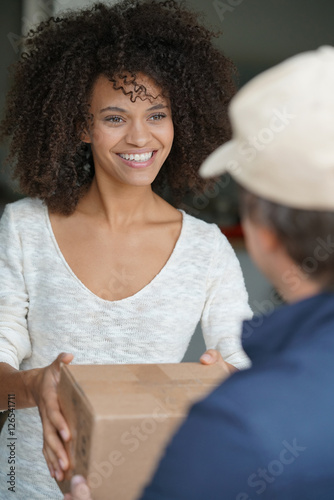 Принти на полотні Mixed race woman receiving package from delivery man