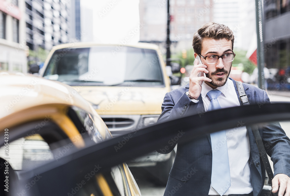 USA, New York City, businessman in Manhattan on cell phone entering a taxi USA, New York City, businessman in Manhattan on cell phone entering a taxi