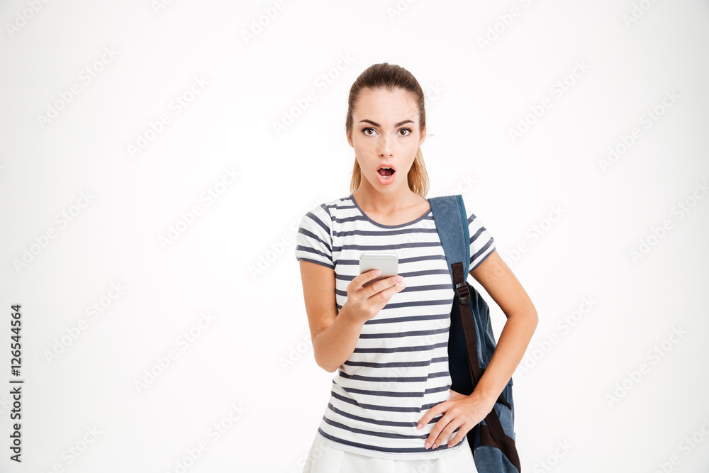 Surprised woman with backpack holding smartphone and looking at camera Surprised woman with backpack holding smartphone and looking at camera