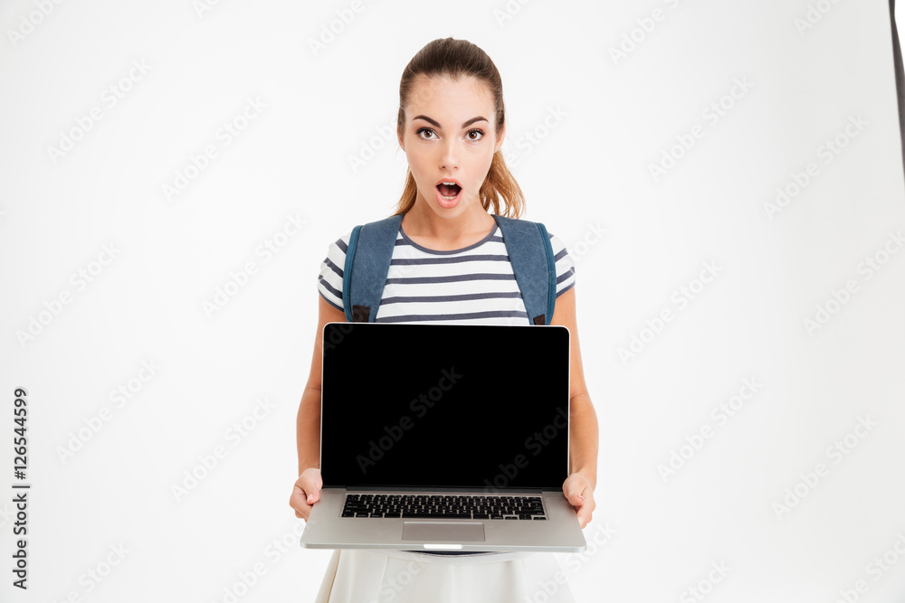 Surprised young woman with backpack holding blank screen laptop Surprised young woman with backpack holding blank screen laptop
