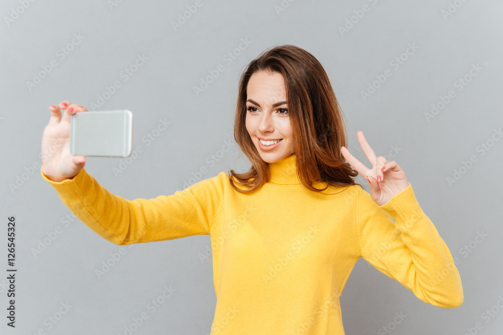 Lovely playful young woman taking selfie with mobile phone Lovely playful young woman taking selfie with mobile phone