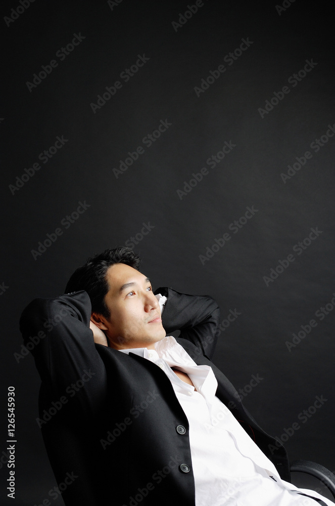 Man sitting, leaning back, hands on head