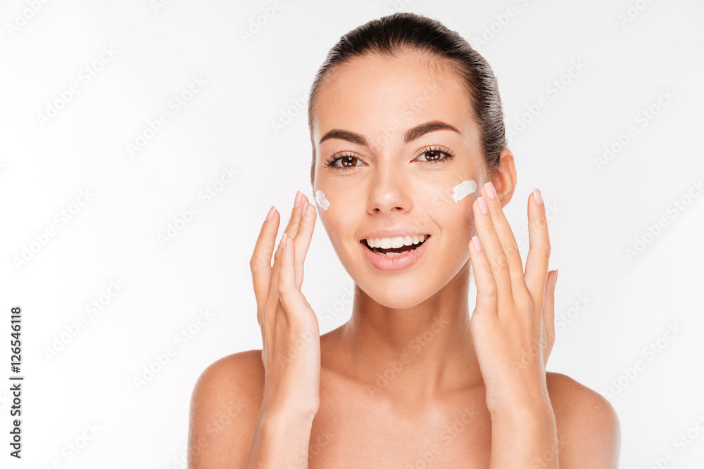 Beautiful young woman applying cosmetic cream treatment on her face Beautiful young woman applying cosmetic cream treatment on her face