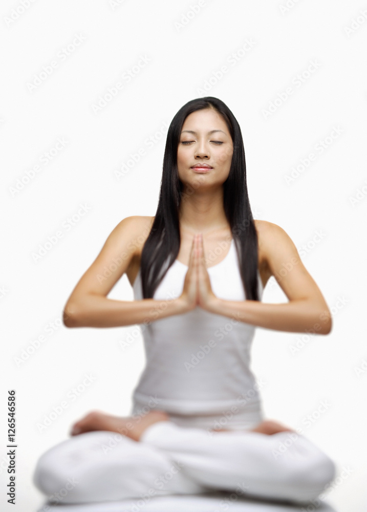Woman practicing yoga, sitting in lotus position, hands together Woman practicing yoga, sitting in lotus position, hands together