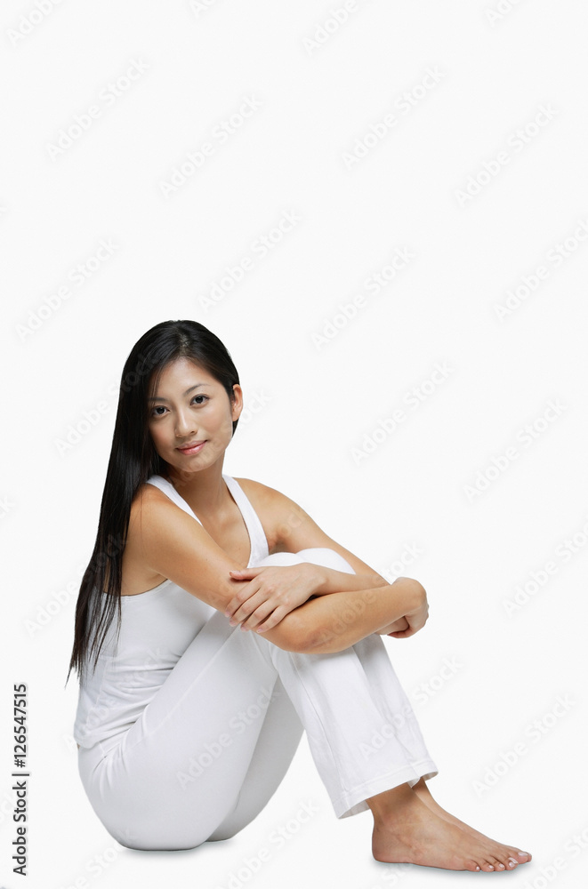 Woman sitting on floor, hugging knees, looking at camera Woman sitting on floor, hugging knees, looking at camera