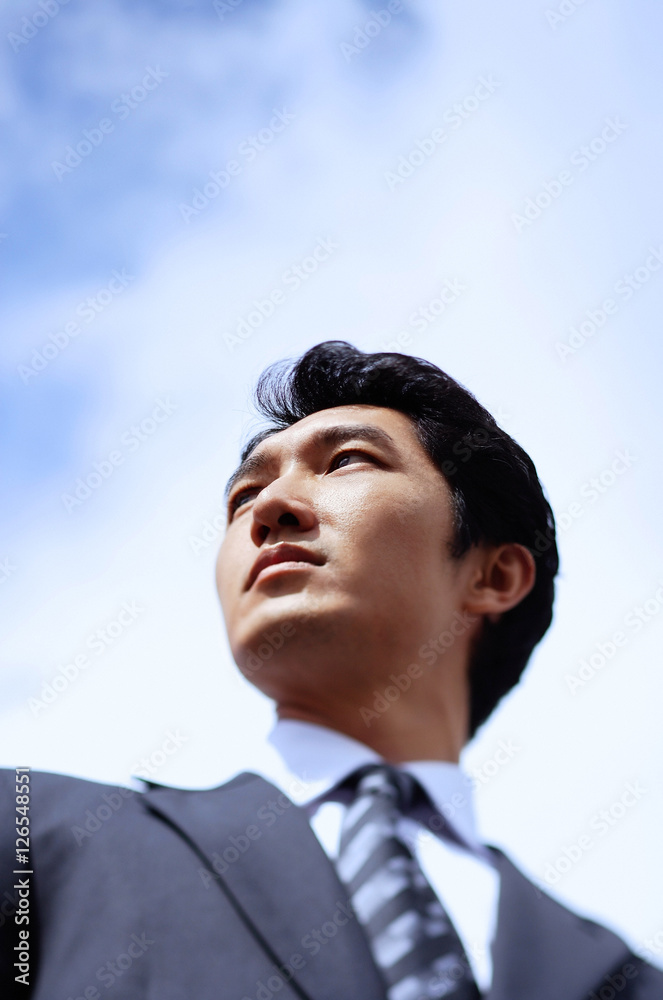 Businessman, looking away, head shot, low angle view
