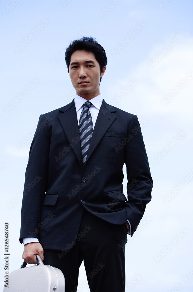 Businessman standing with briefcase, looking at camera Businessman standing with briefcase, looking at camera