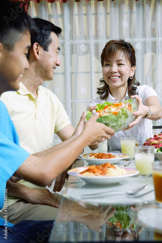 Mother passing salad bowl to family members