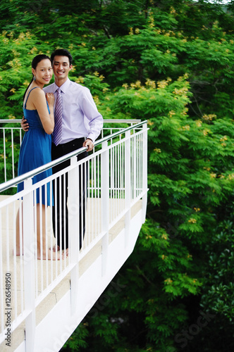 Couple standing on balcony,  looking at camera