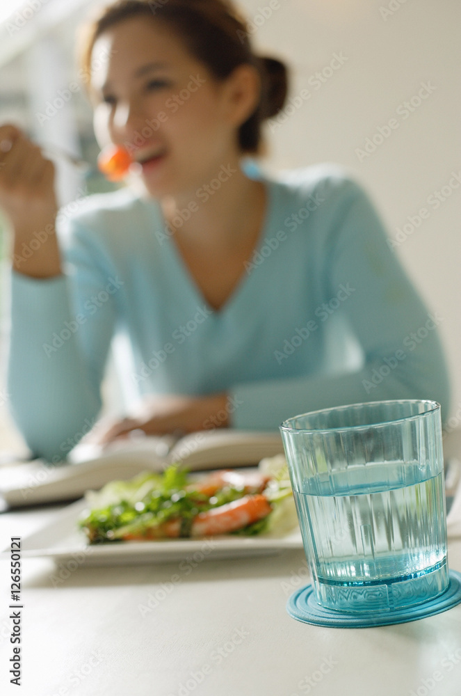 Young woman eating salad, focus on the foreground