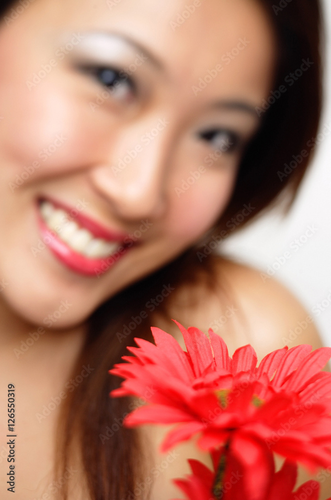 Woman with flower, smiling, focus on the foreground