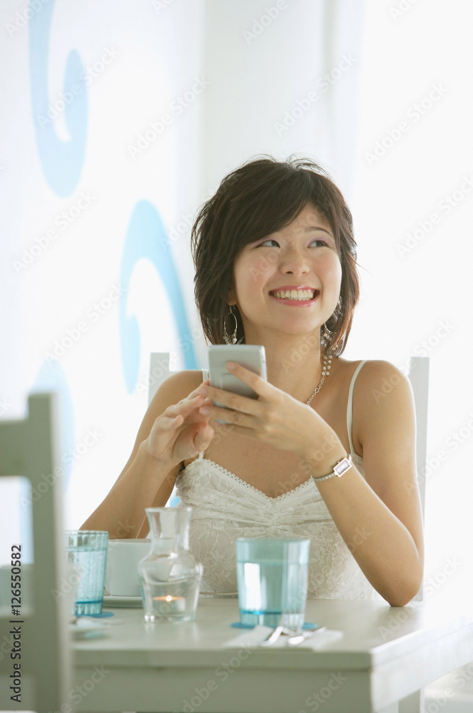 One woman sitting in cafe, holding compact, smiling One woman sitting in cafe, holding compact, smiling