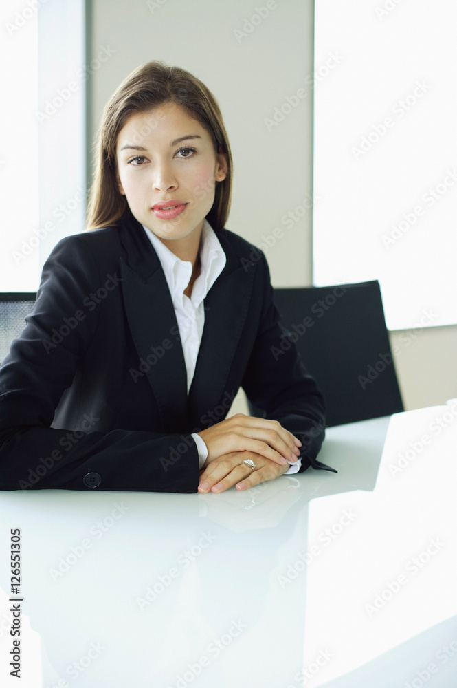 Businesswoman sitting at table, looking at camera Businesswoman sitting at table, looking at camera