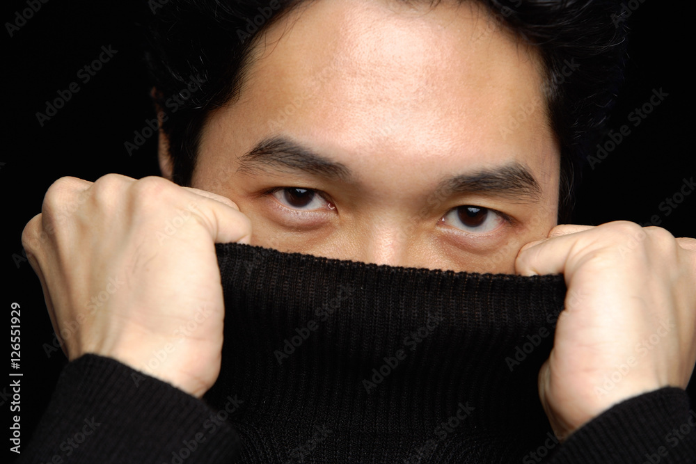 Man pulling turtleneck over face, looking at camera