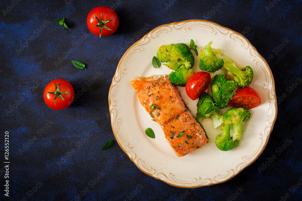 Baked fish salmon garnished with broccoli and tomato. Dietary menu. Fish menu. Seafood - salmon. Top view Baked fish salmon garnished with broccoli and tomato. Dietary menu. Fish menu. Seafood - salmon. Top view