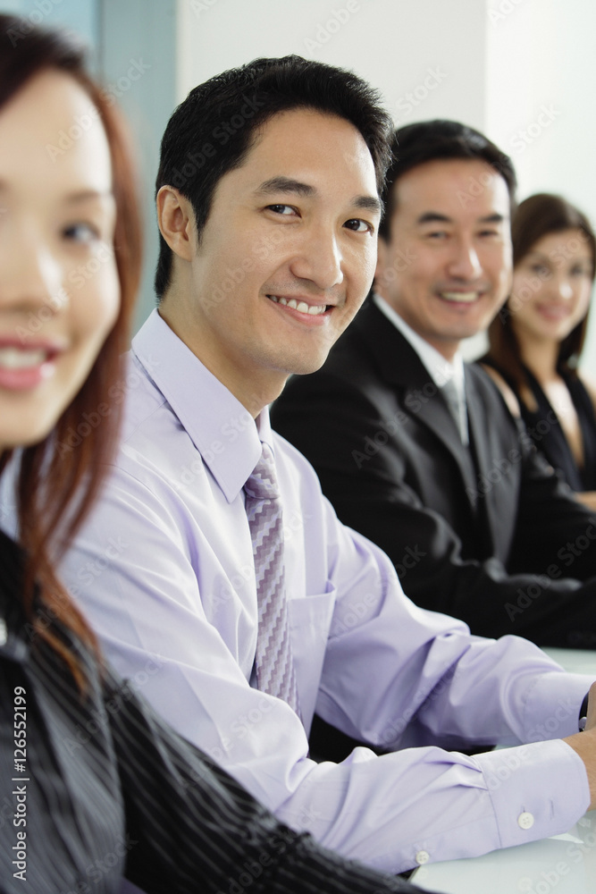 Business people sitting in a row, smiling at camera Business people sitting in a row, smiling at camera