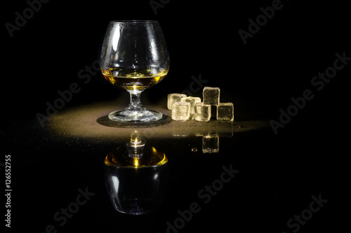Whiskey in glass and ice on a black background.
