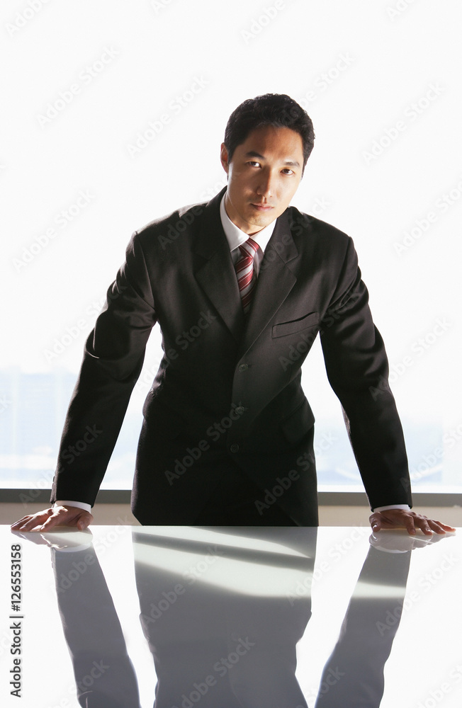 Businessman leaning on table, looking at camera