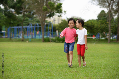 Young girls walking on grass, in park