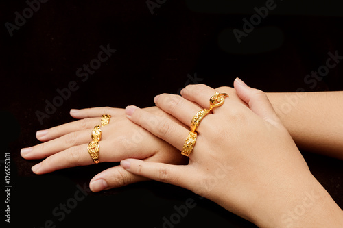 woman's hand with many different gold rings on black background