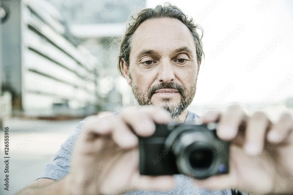 Mann fotografiert mit seiner digitalen Kompaktkamera