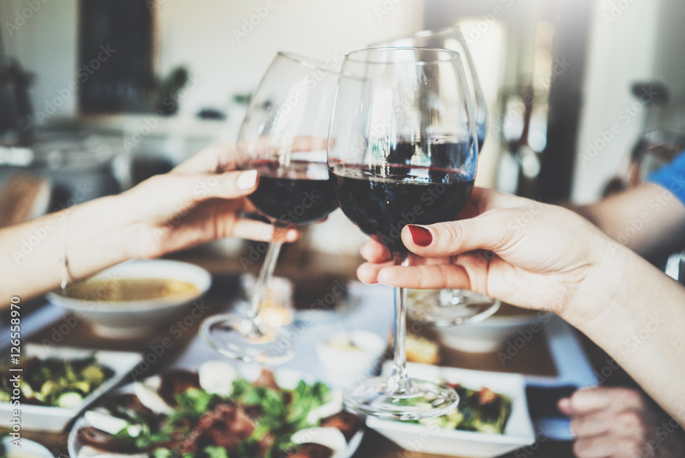 Young happy friends cheering with glasses of red wine, family dinning at home, enjoyment and party concept, homemade cuisine and healthy food concept