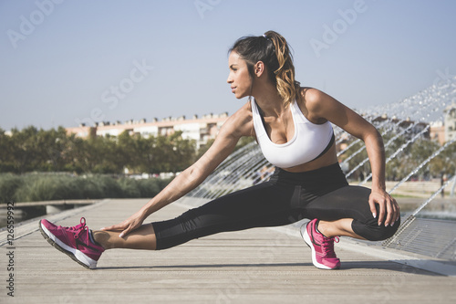 Fényképezés Attractive woman doing stretching exercises outdoors