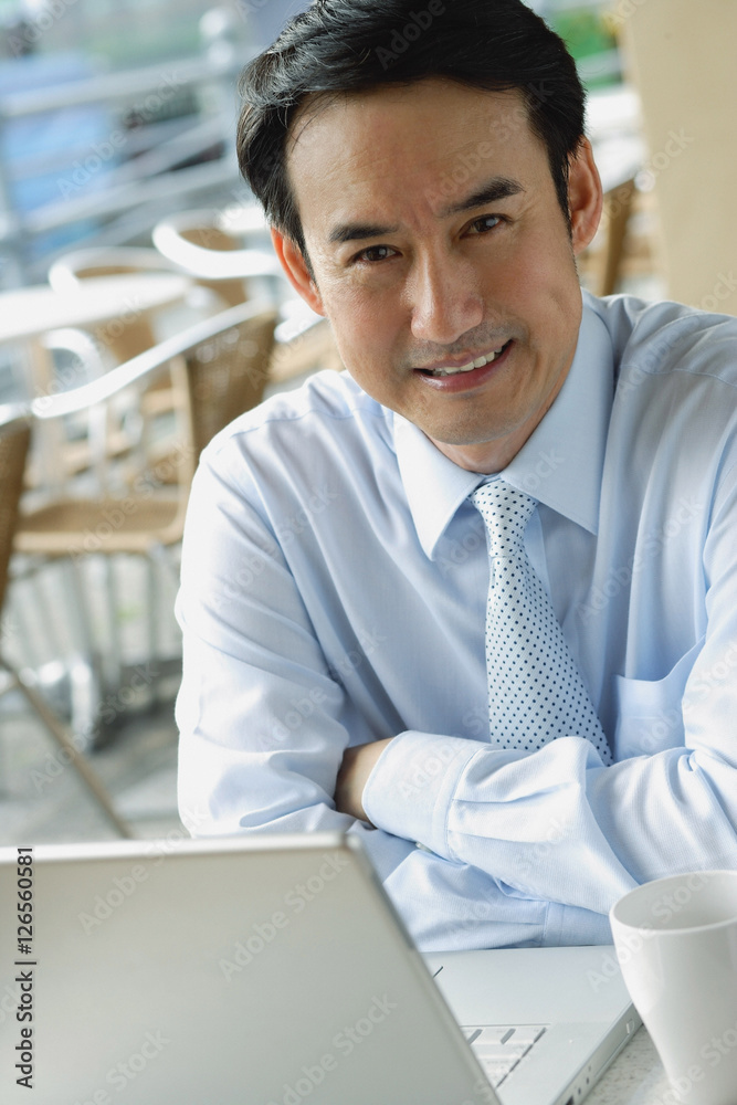 Businessman in cafe with laptop, smiling at camera Businessman in cafe with laptop, smiling at camera