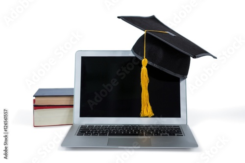 Laptop with mortarboard and books