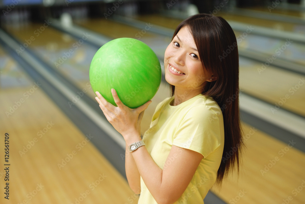 Woman at bowling alley holding green bowling ball