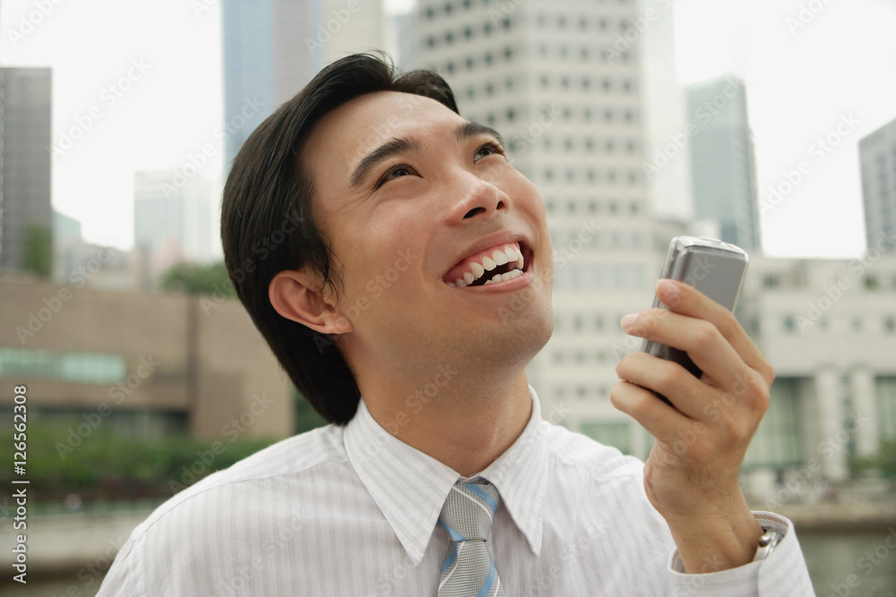 Businessman holding mobile phone, buildings in the background Businessman holding mobile phone, buildings in the background