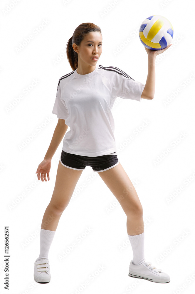 Young woman standing, holding volleyball in one hand Young woman standing, holding volleyball in one hand